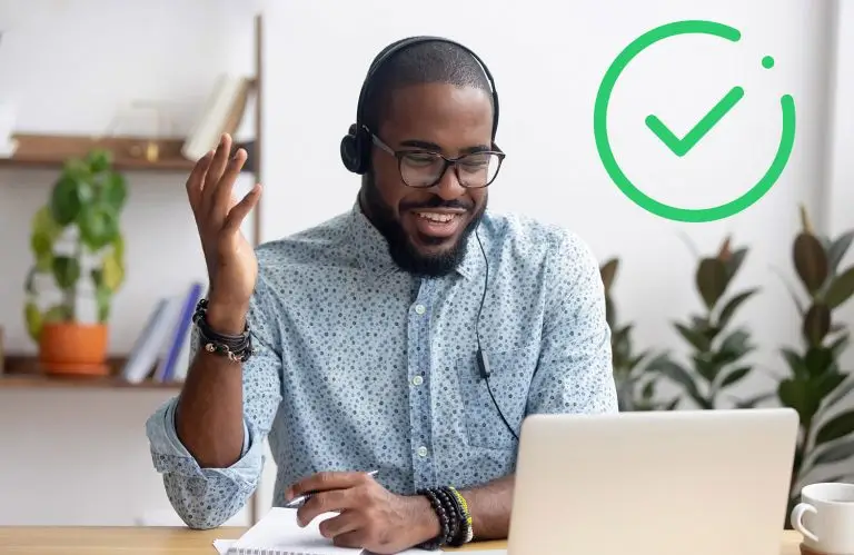 Smiling African American employee in headphones using laptop, looking at screen, making video call or watching webinar, writing notes, distance learning language concept, call center operator working